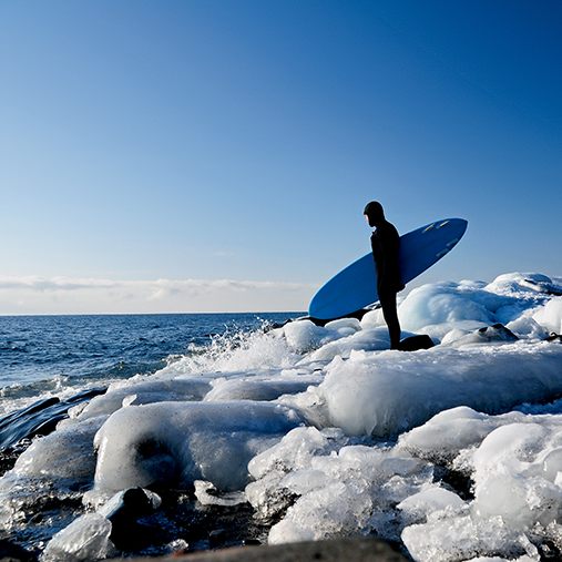 Surfer On Icy Shoreline