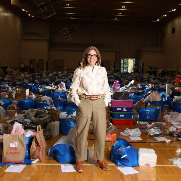 56 Main Jenny Welsh, Founder Of Growing Cents Of Style, Standing In Front Of Gently Used Items Ready To Be Cataloged And Sold Online.