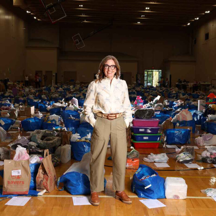 56 Main Jenny Welsh, Founder Of Growing Cents Of Style, Standing In Front Of Gently Used Items Ready To Be Cataloged And Sold Online.