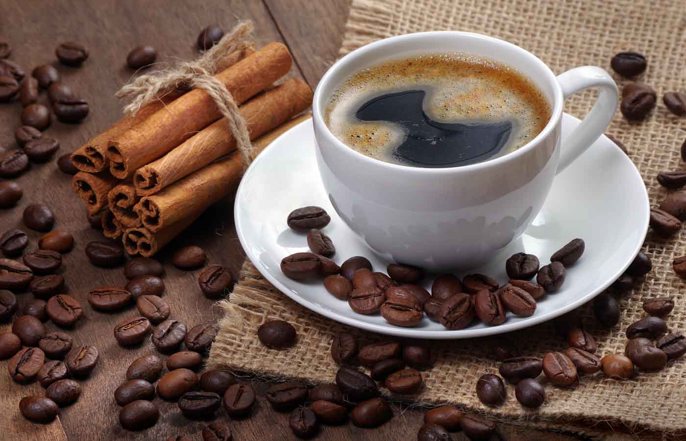 Coffee Beans And Cup Of Coffee On A Wooden Table. Coffee In A White Cup.